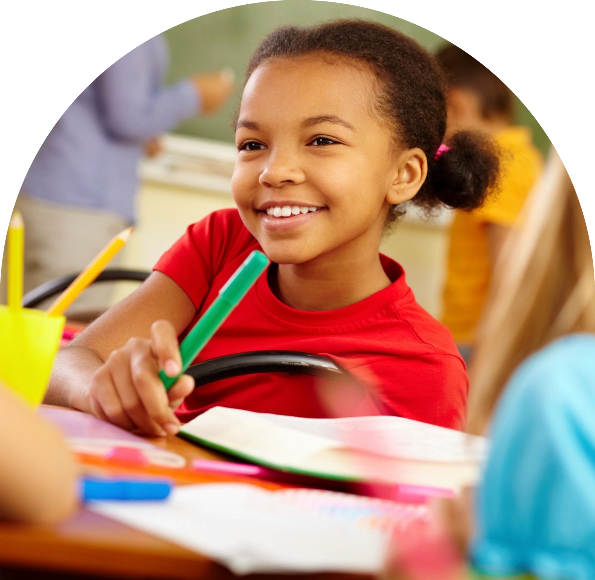 A young boy smiles while holding a pair of green pencils.